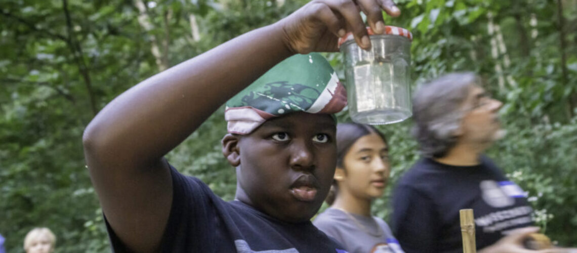 Boy captures a firefly in a jar to inspect.